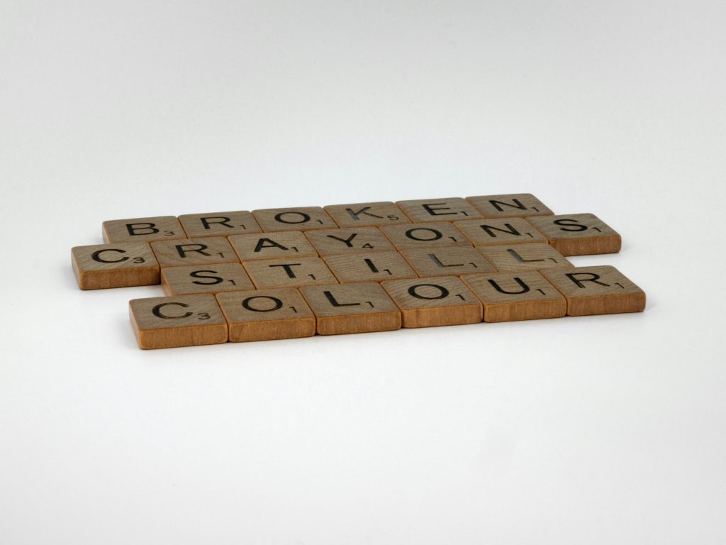 Wooden game tiles that spell out, "Broken Crayons Still Color".