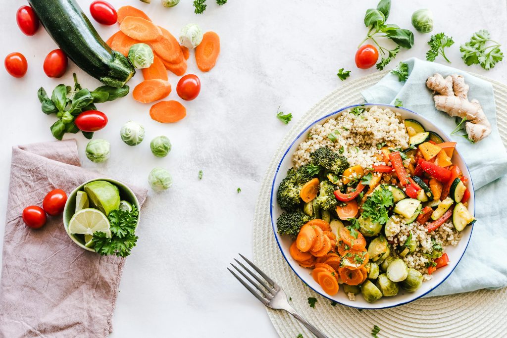 Brightly colored vegetables and a salad on a light colored tablecloth.