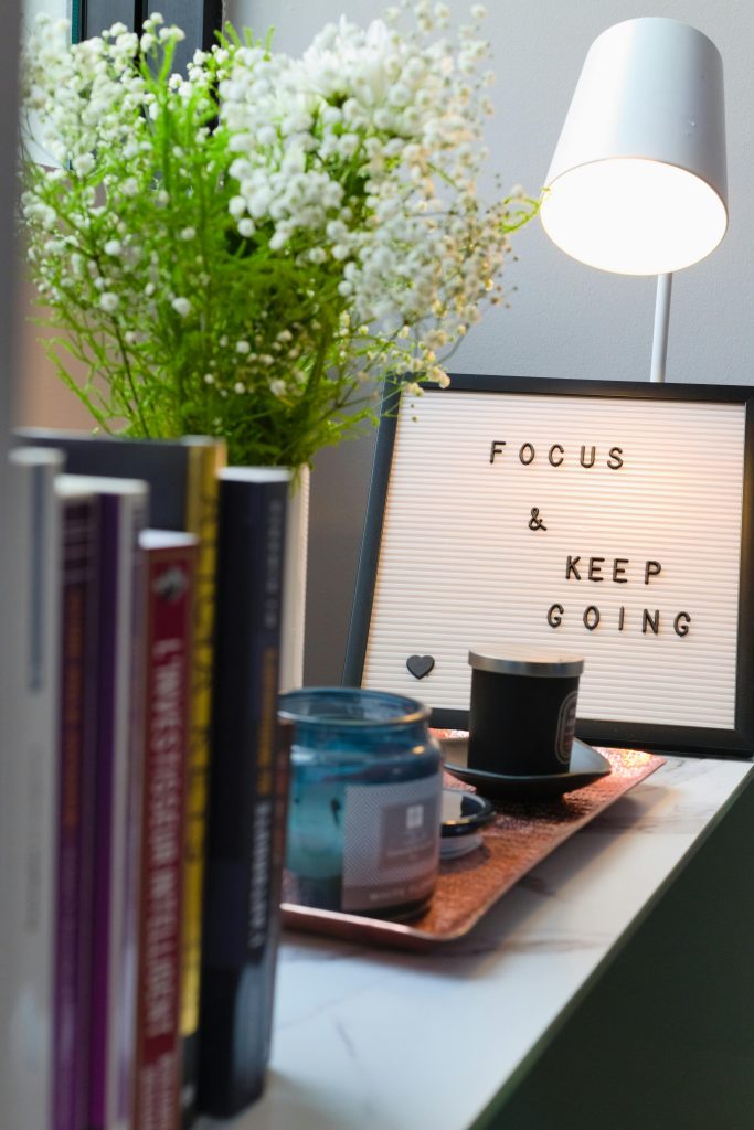 Bright, joyful looking bookshelf with a sign that says "Focus and Keep Going".